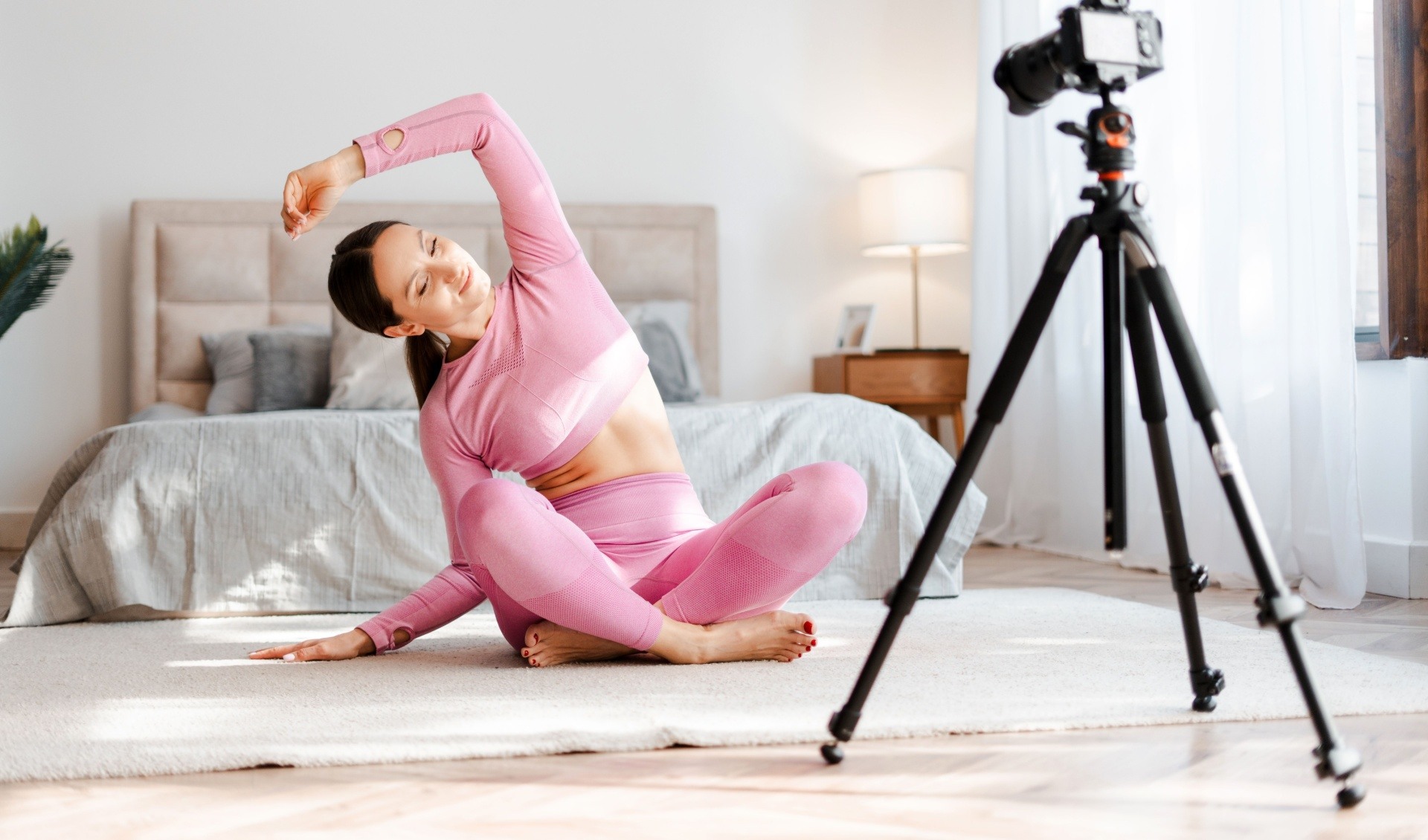 Woman in fitness attire recording herself doing exercise for a online course 