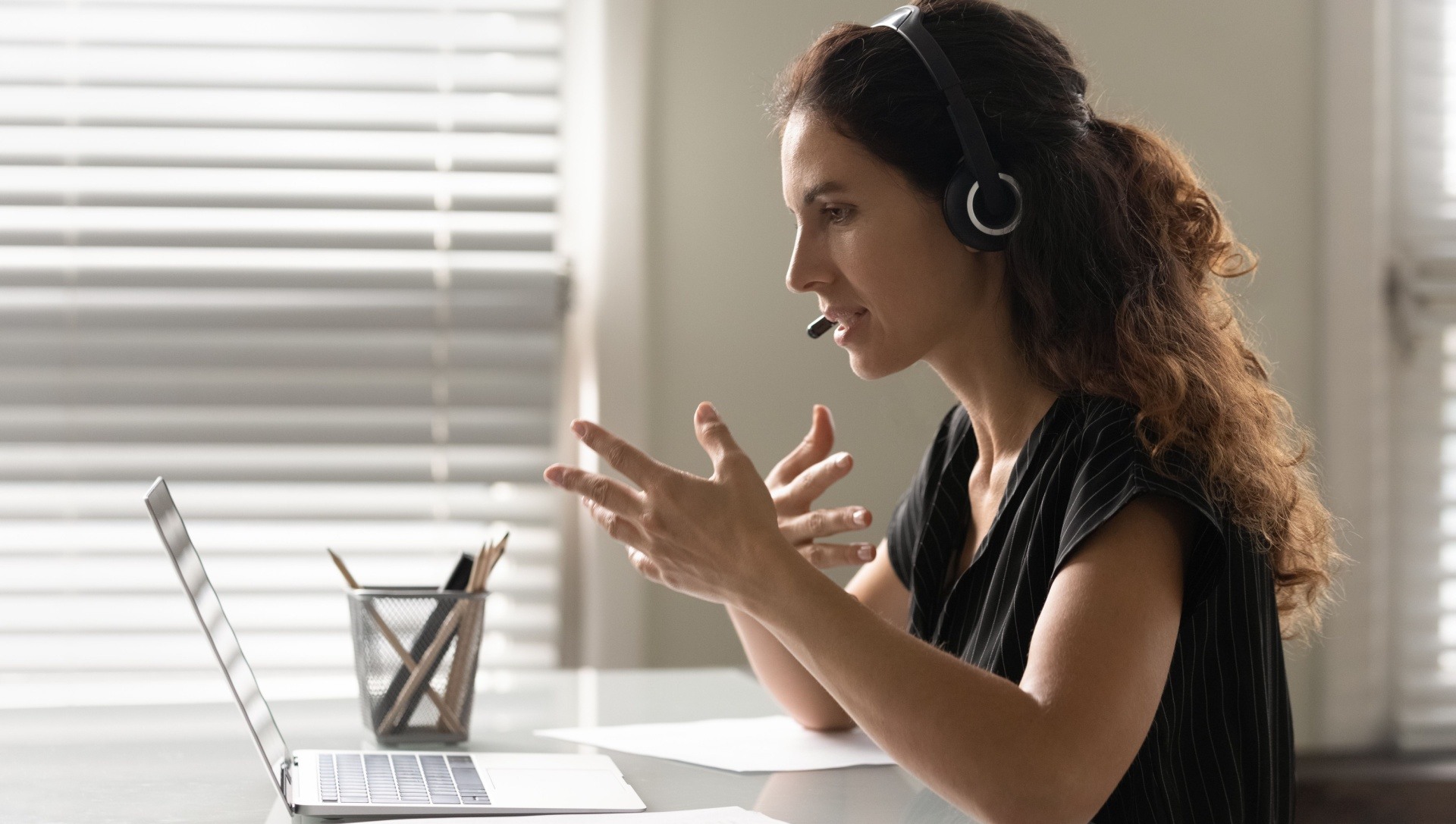 Woman on laptop speaking on a video call with a headset on 