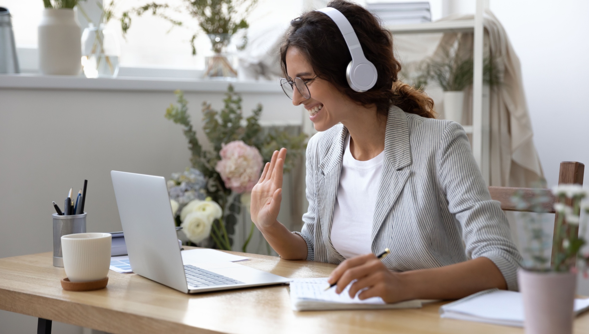 woman sat down with a headset on, while being on her laptop talking to people on the other end.