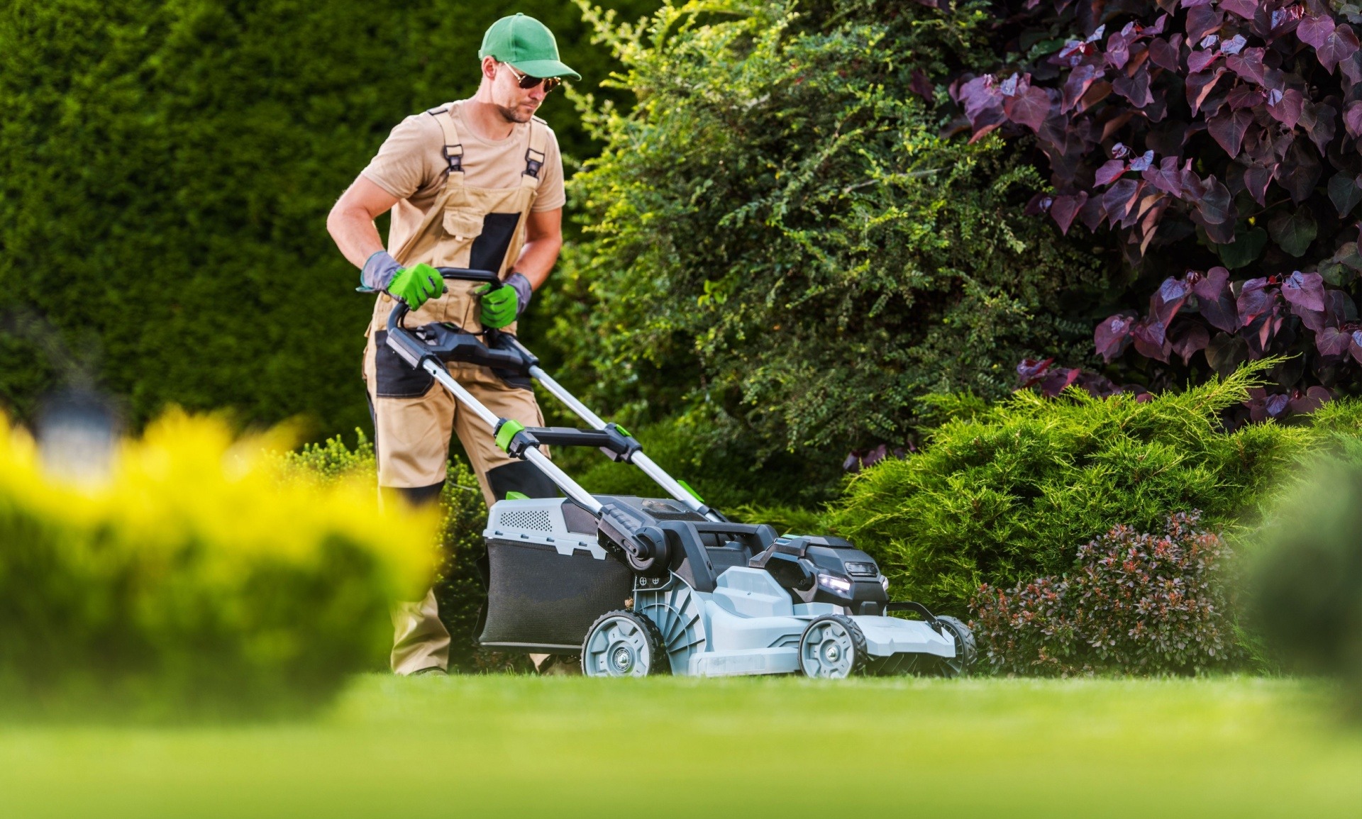 Man mowing the lawn with personal protective equipment 