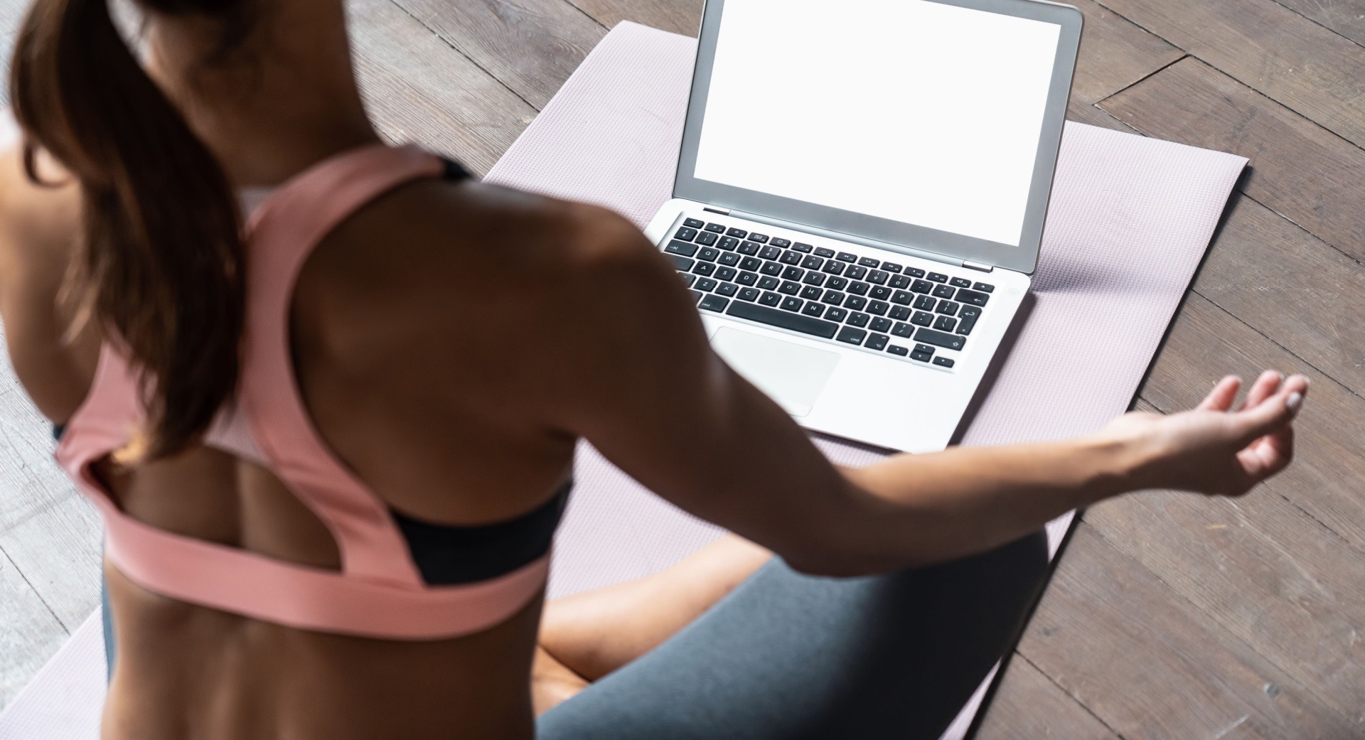 Woman sat in front of laptop doing yoga to sell online courses