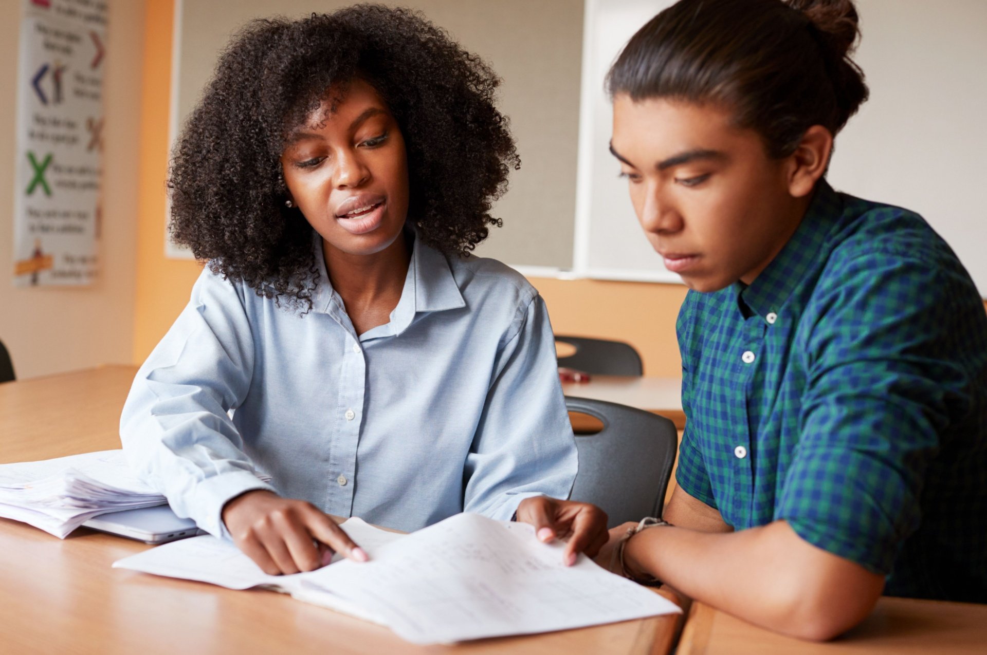 Woman wearing blue shirt tutoring a young man wearing a darker blue shirt