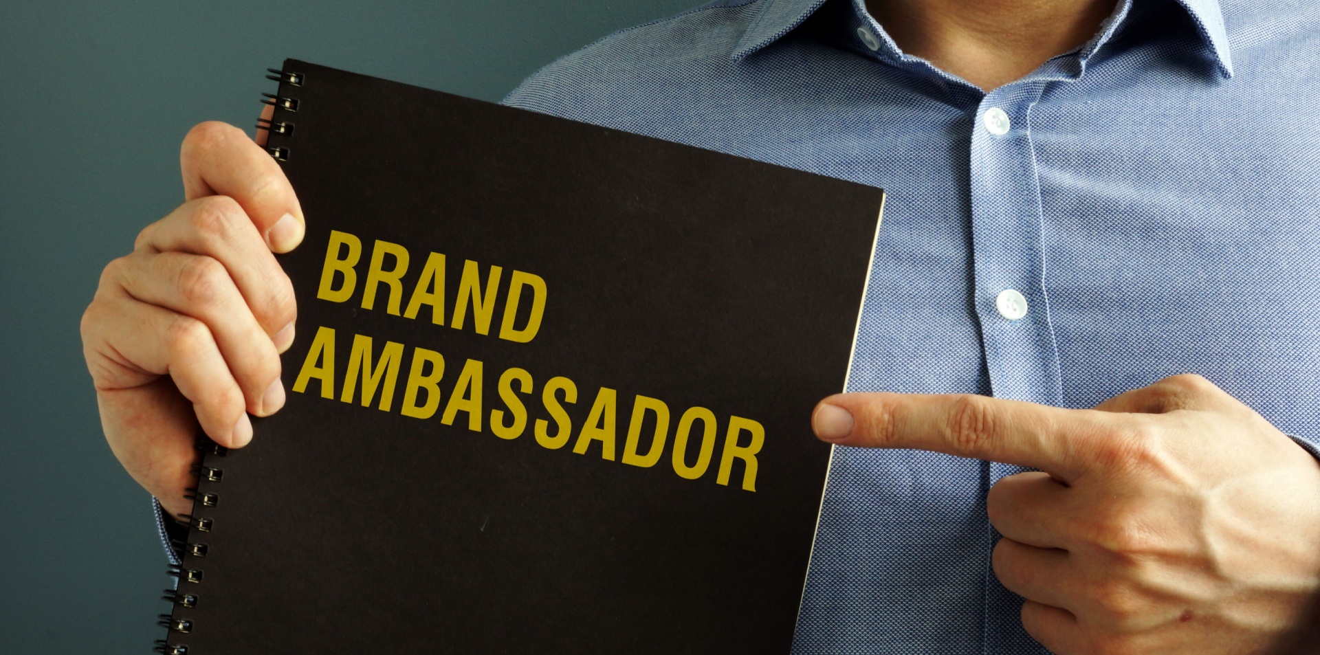 man holding a black book that says brand ambassador on the front it 