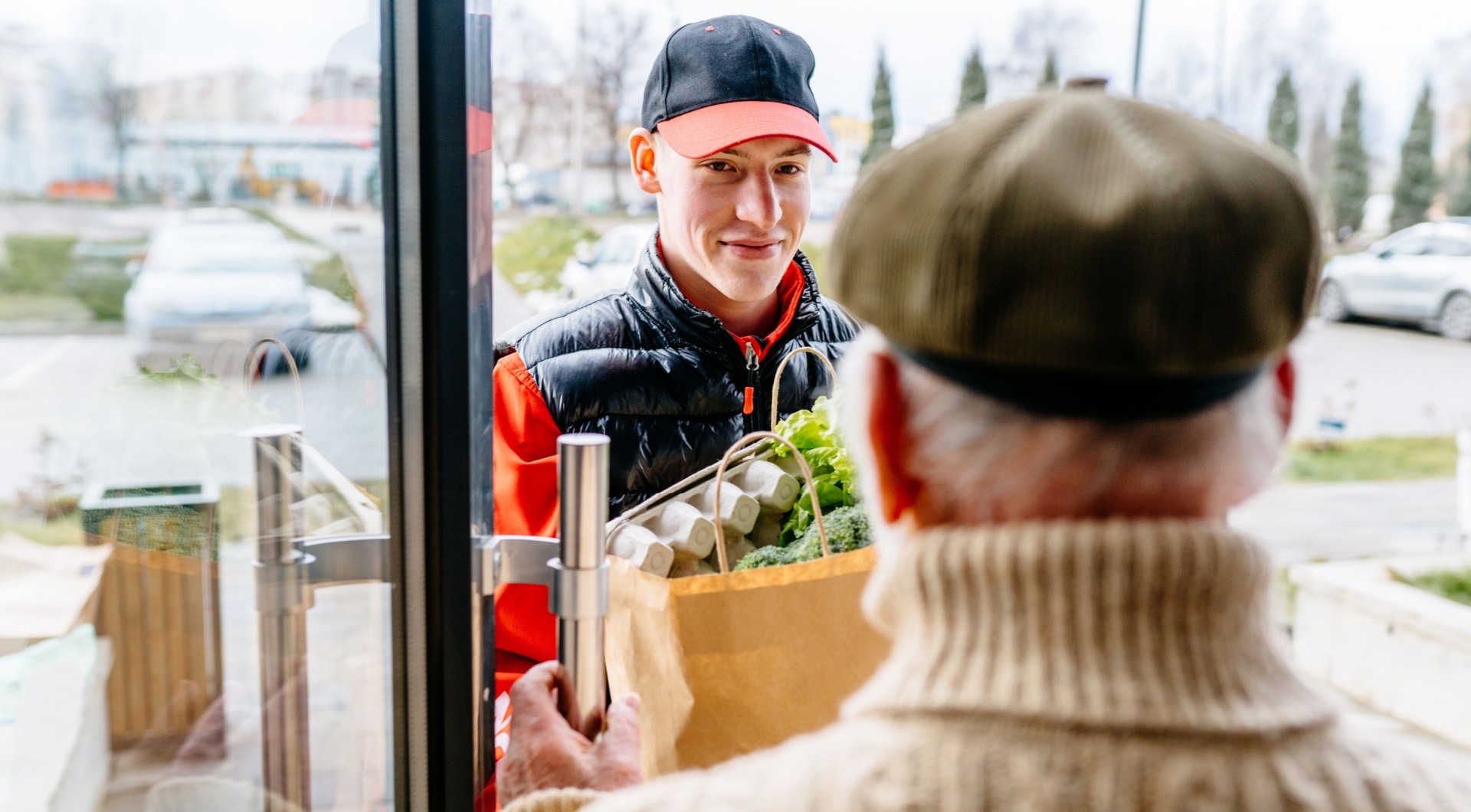 man delivering groceries to an elderly man smiling at the door 