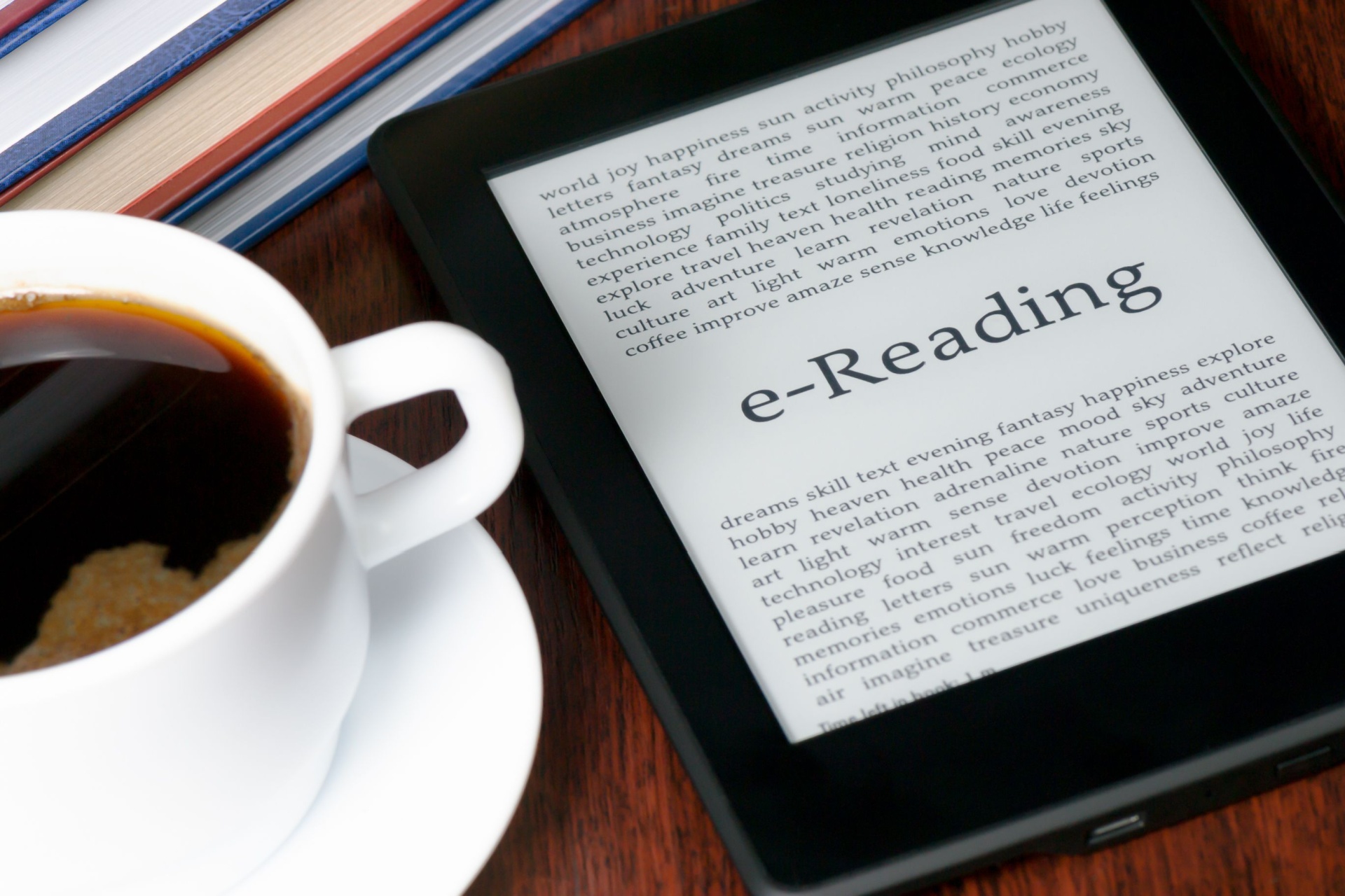 electric book reader on a table with a coffee in a mug next to it. 