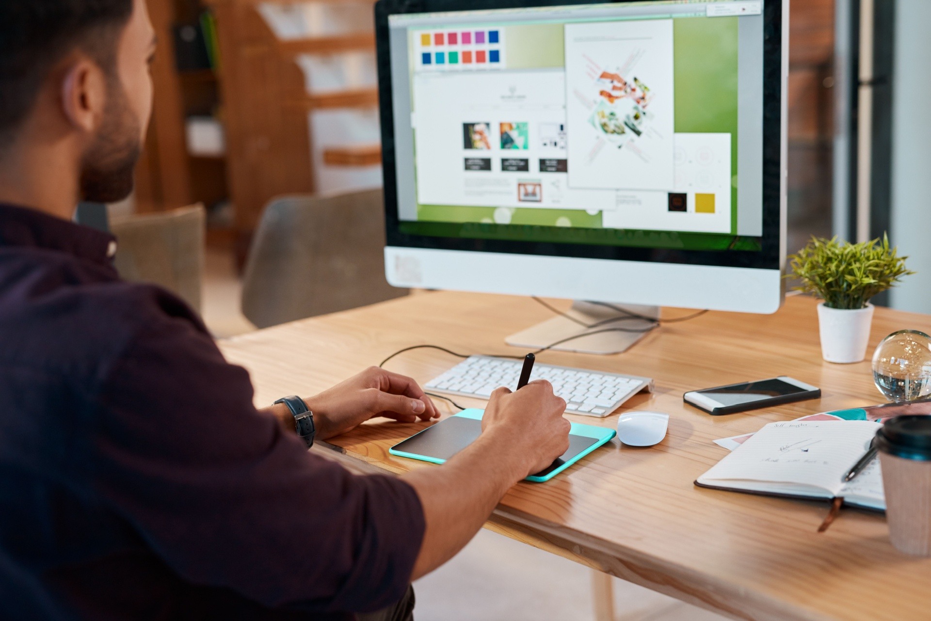 Man sitting at his computer doing graphic design on a tablet.