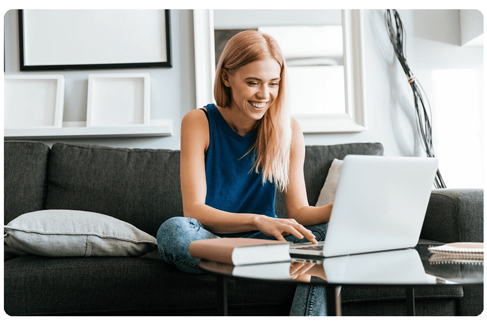 happy-woman-sitting-sofa-using-laptop-home-1-scaled