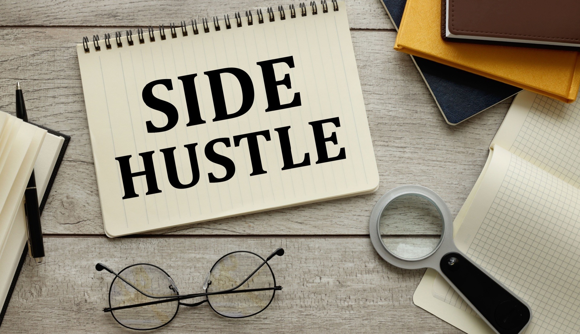 Side hustle graphic with some books an glasses spread around it 