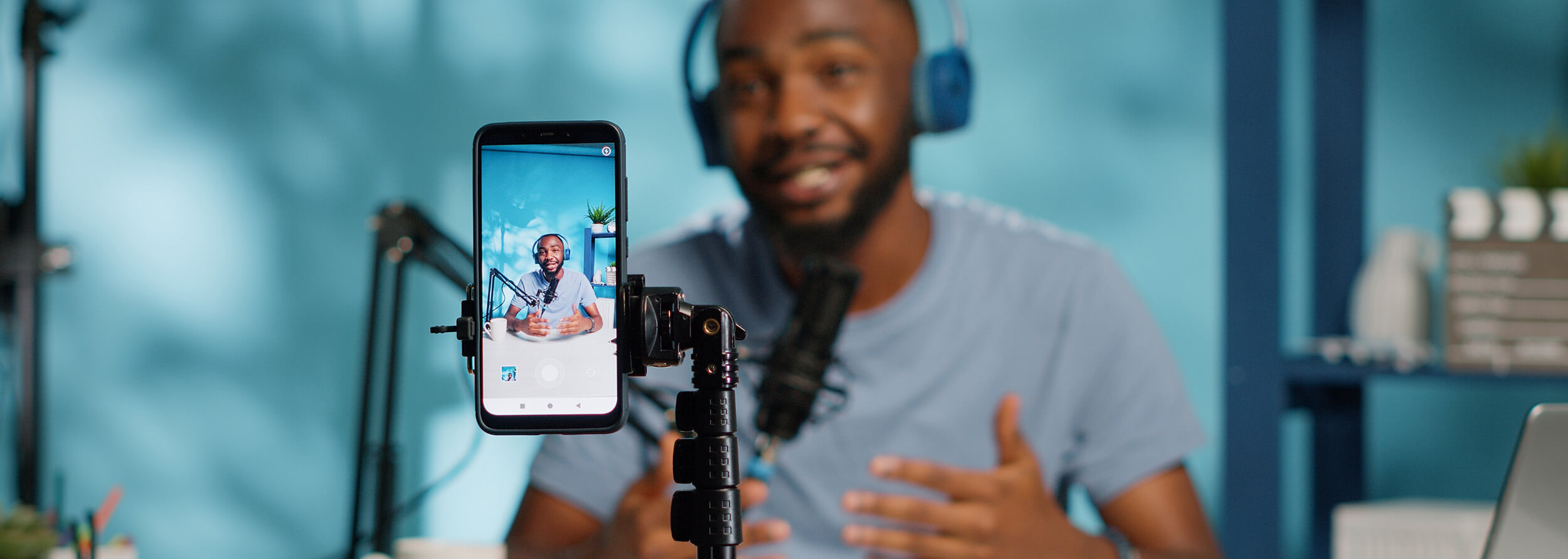 Man talking into a microphone holding a phone recording himself speaking