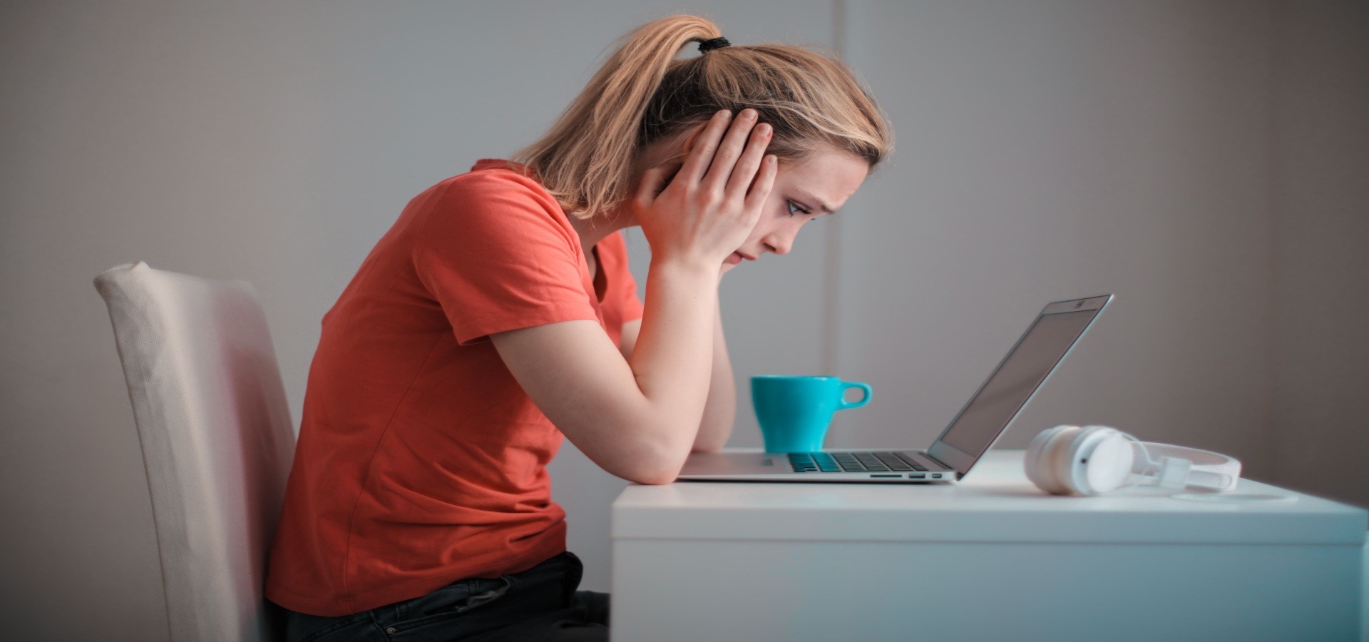 woman with head in hands staring at laptop screen