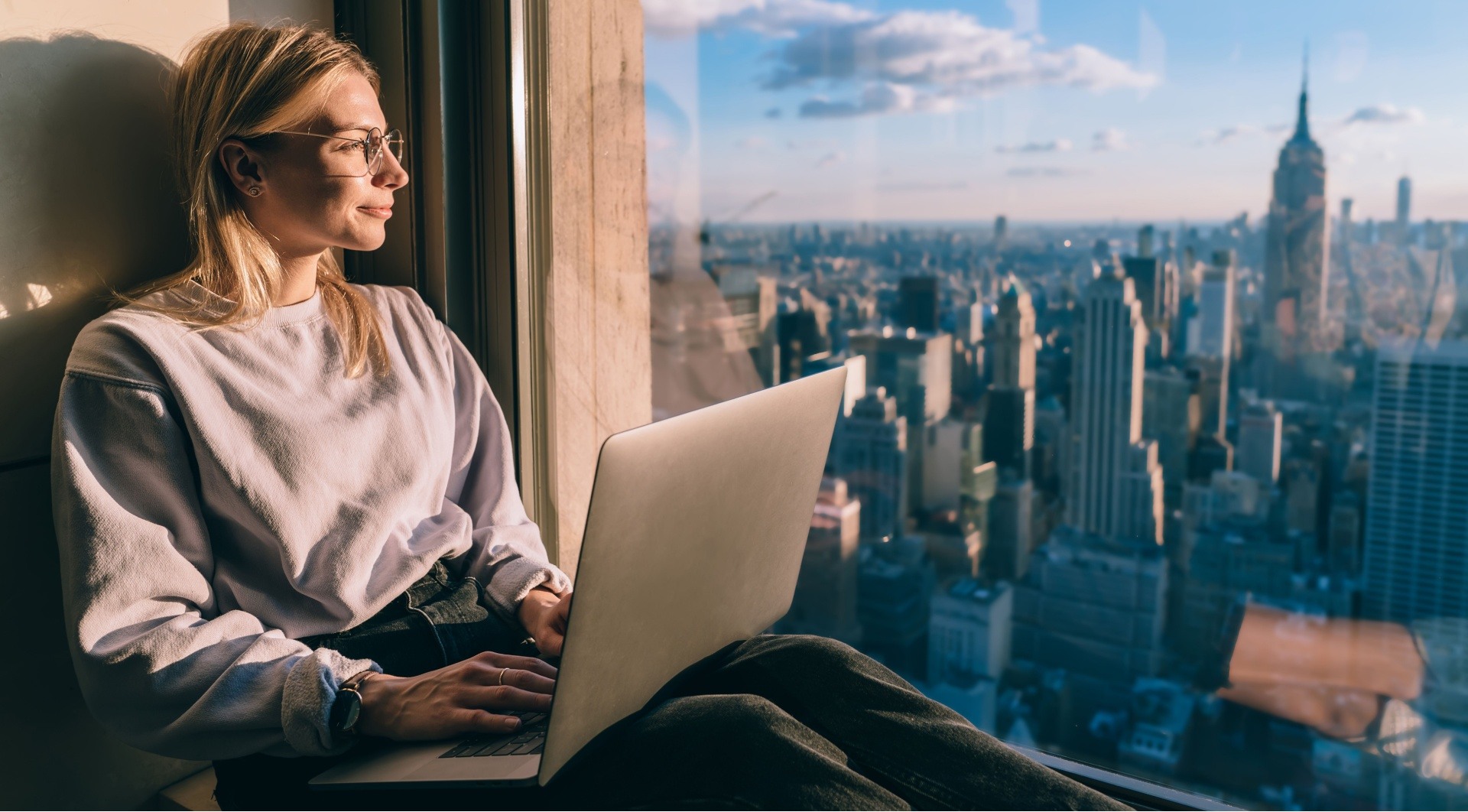 woman on laptop looking over a great city view