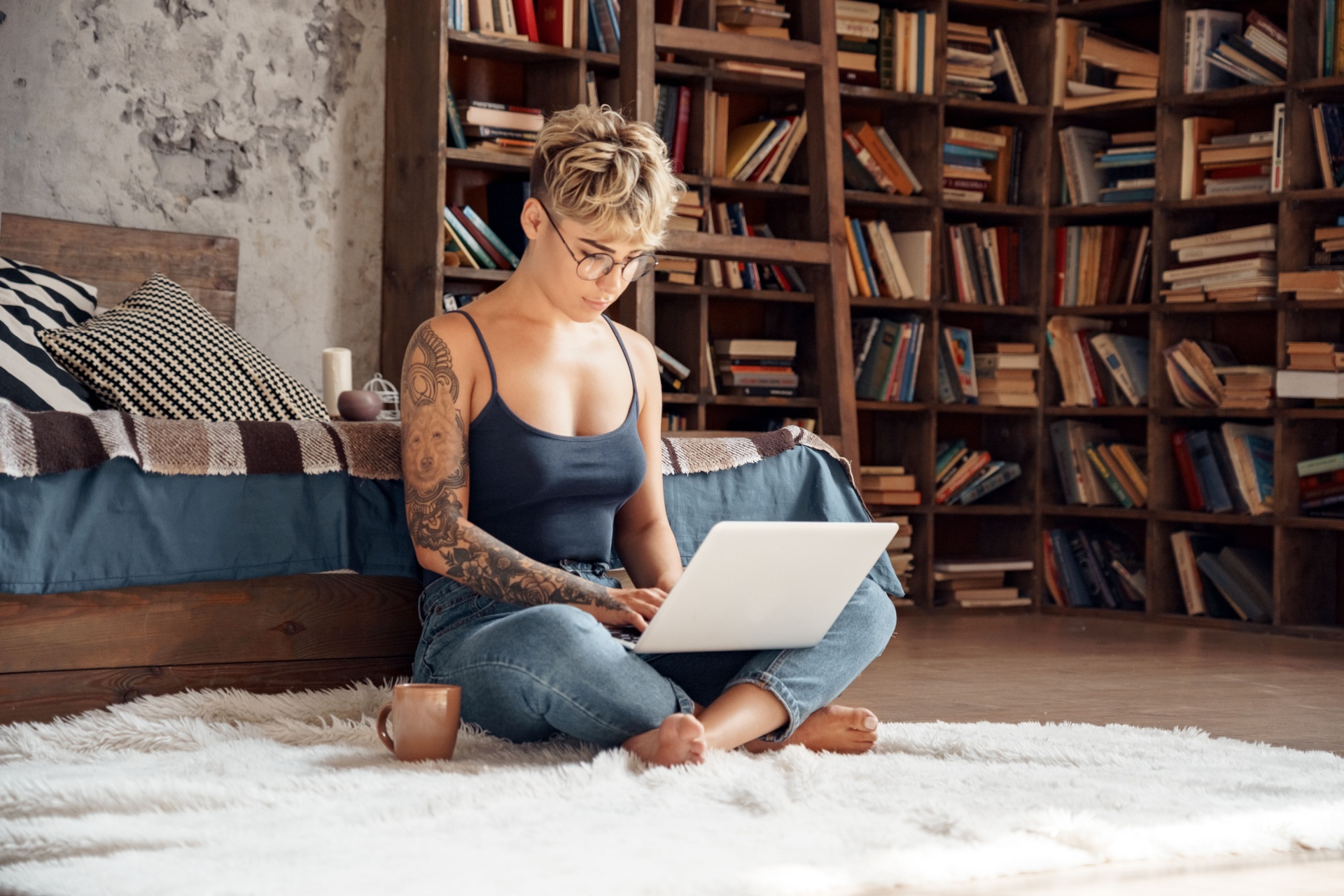 Woman sat on the floor on her laptop doing work with glasses on