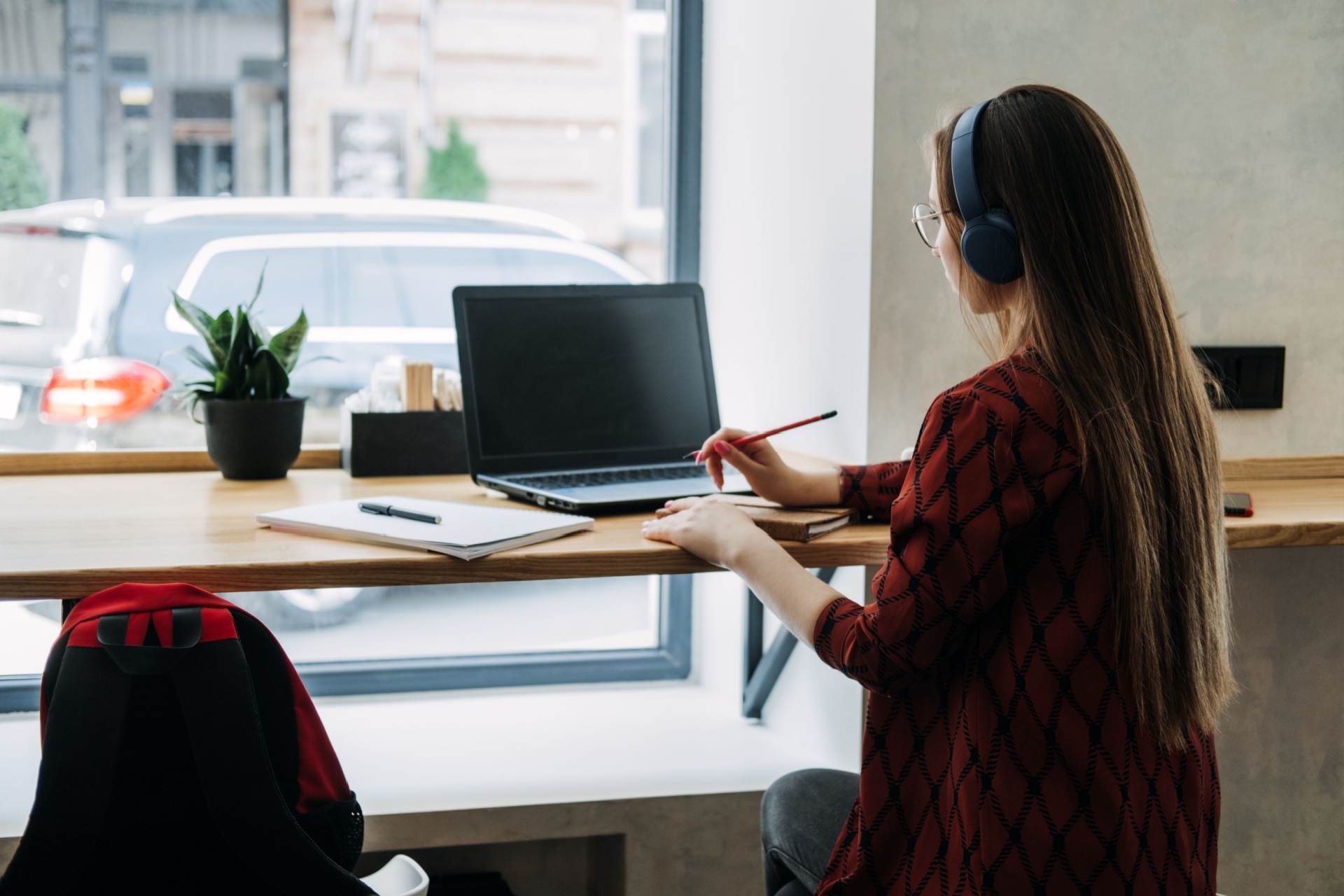 Woman sitting down at a desk on a laptop with an open view window infront of her.