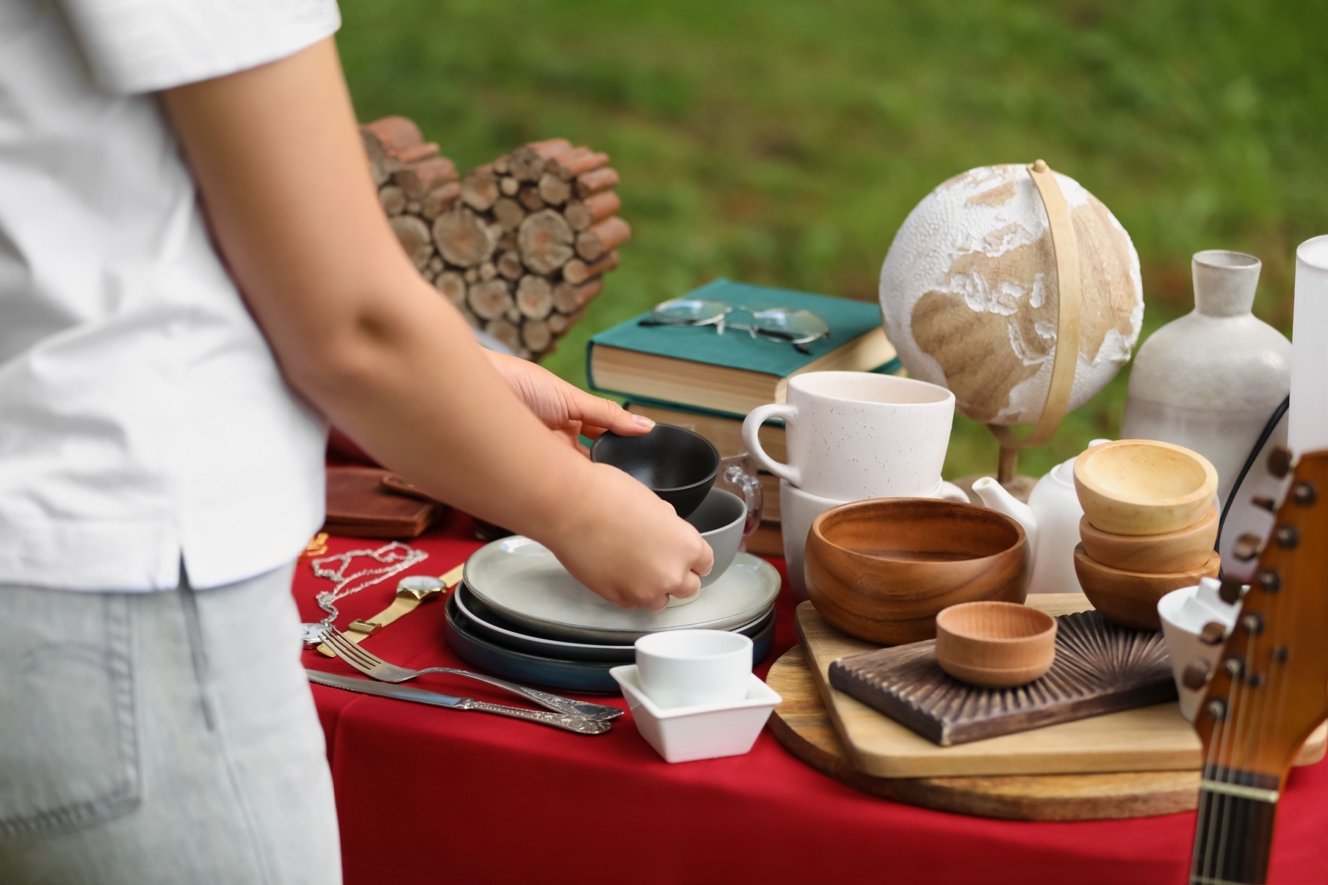 Woman holding two bowls on beautiful table at a yard sale/ garage sale